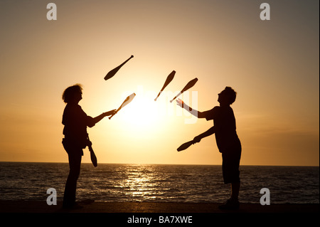 Due persone che l uomo e la donna giovane giocoleria con i club al tramonto sul lungomare di Aberystwyth Wales UK Foto Stock