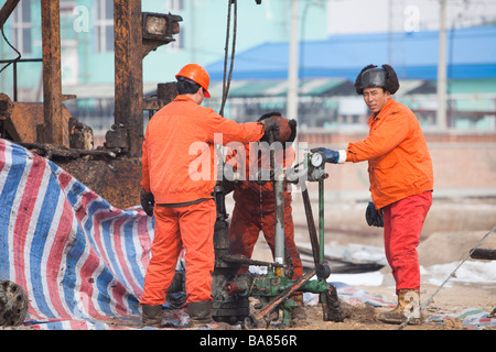 Lavoratori di olio la perforazione di un nuovo pozzo petrolifero di Daqing campo petrolifero nel nord della Cina Foto Stock