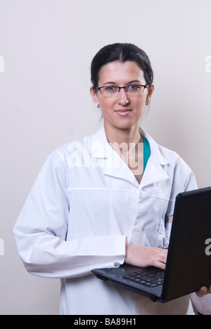 Medico che lavorano su computer portatile guardando la telecamera Foto Stock