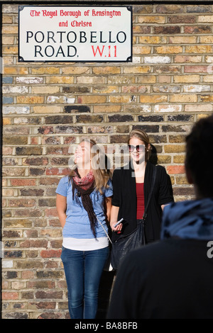 Londra, Regno Unito. I turisti che posano per una foto al di sotto di Portobello Road sign in il mercato Foto Stock