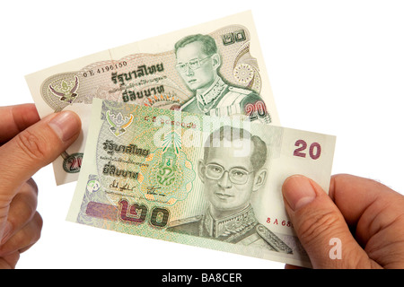 Maschio di denaro mani tenendo il vecchio e il nuovo 20 Thai baht valuta banconote Foto Stock