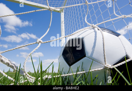 Pallone da calcio nell obiettivo net contro il cielo blu Foto Stock