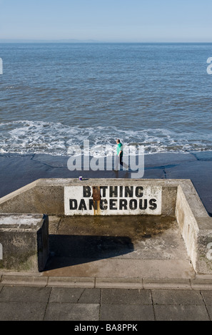 Un uomo che cammina su asfalto Lungomare spiaggia in Porthcawl in Galles. Foto di Gordon Scammell Foto Stock