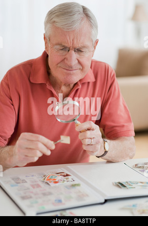 Senior uomo guardando alla raccolta di francobolli Foto Stock