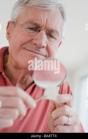 Senior uomo guardando alla raccolta di francobolli Foto Stock