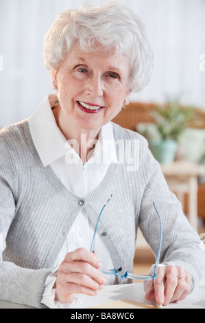 Ritratto di donna senior seduta a tavola Foto Stock