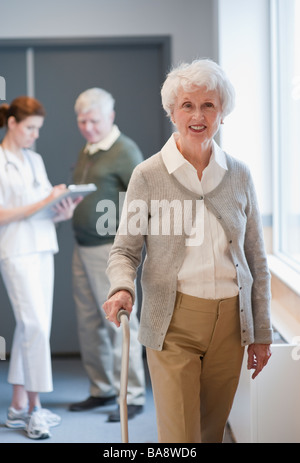 Senior Donna che cammina con la canna da zucchero Foto Stock