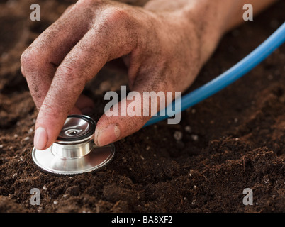 Donna ascolto di terreno con uno stetoscopio Foto Stock