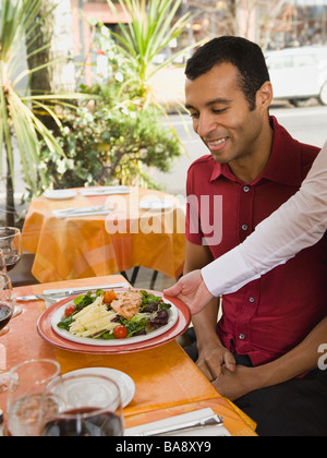 Cameriere che serve cibo per l'uomo in ristorante Foto Stock