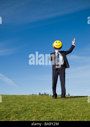 Imprenditore azienda Smiley face palloncino sulla faccia Foto Stock