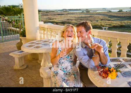 Coppia felice di ridere con lo champagne sul balcone Foto Stock