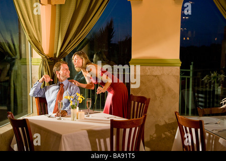 Metà di uomo adulto girando per ricevere il bacio da donna in ristorante Foto Stock