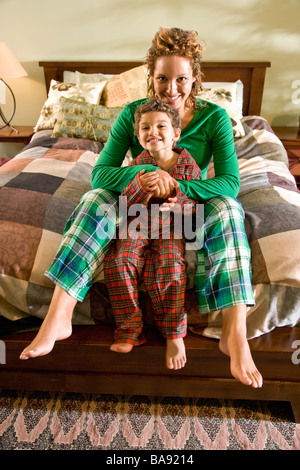 Afro-americano di madre e bambino in pigiama sul letto Foto Stock