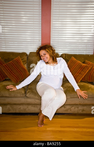 Ritratto di sorridere e africana incinta donna americana sul divano Foto Stock