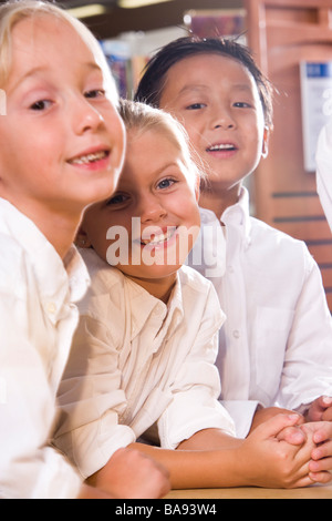 Ritratto di scuola elementare i bambini seduti a tavola in libreria Foto Stock