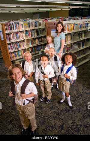 Ritratto di insegnante di scuola elementare con alunni in biblioteca Foto Stock