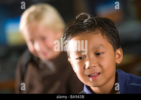 Ragazzo asiatico in piedi nella biblioteca della scuola Foto Stock