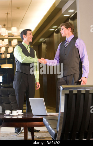 Ritratto di multi-razziale imprenditori stringono le mani nella lobby moderna Foto Stock