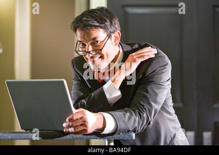 Imprenditore lavora su laptop dando se stesso pacca sulla spalla Foto Stock