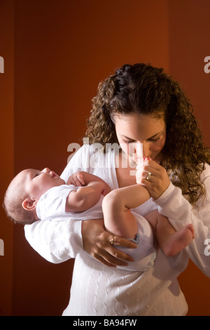 Ritratto di Madre kissing 3 mesi di età del bambino in piedi Foto Stock