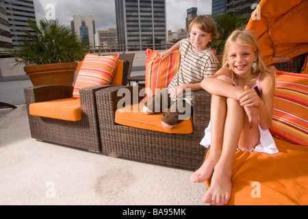 Ritratto di due bambini seduti sulla terrazza sul tetto in città Foto Stock