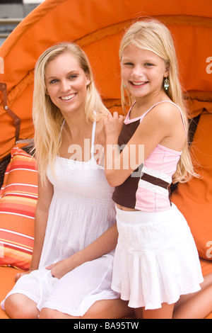 Ritratto di sorridente madre e figlia seduti su sedie di colore arancione Foto Stock