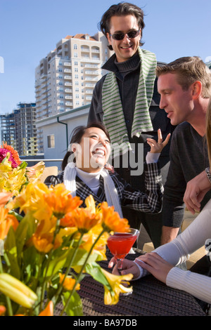 Coppie giovani di relax con un drink sulla terrazza del tetto del centro cittadino di condominio in città Foto Stock