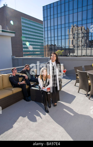 Coppie giovani di relax con un drink sulla terrazza del tetto del centro cittadino di condominio Foto Stock