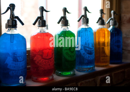 Colorate le bottiglie di soda su un davanzale Foto Stock