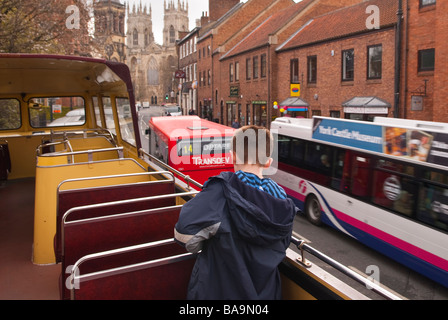 Un giovane ragazzo in aprire il piano superiore di un autobus turistici che viaggiano attraverso la città di York,Yorkshire, Regno Unito Foto Stock