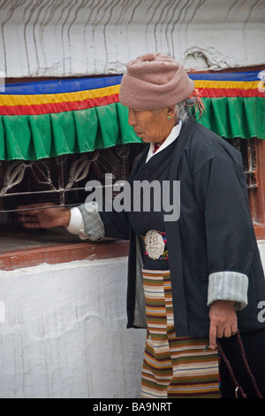 Donna pellegrino a Kathmandu Boudhanath pregando da statua, girando la preghiera mills. Il Nepal Asia 90421 Nepal Foto Stock