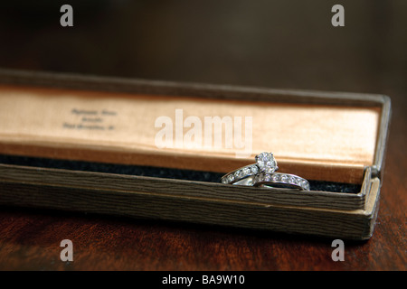 Un diamante e platino womens anello nuziale appoggiata in una lunga scatola di gioielli su una tavola di legno Foto Stock