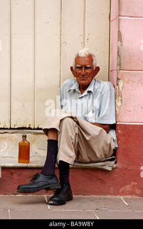 Uomo cubano si siede su una porta in Trinidad Foto Stock