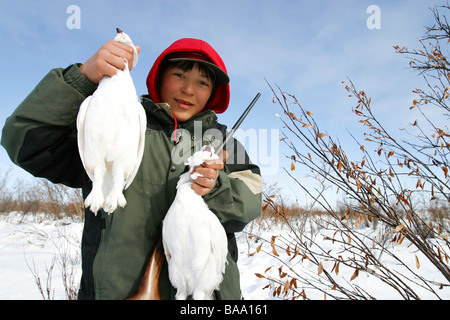 Un giovane Prime Nazioni hunter contiene fino ptarmigan uccelli gioco vicino al Old Crow, Yukon Territory, Canada Foto Stock