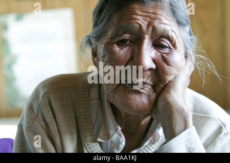 Una delle prime nazioni anziano femmina si siede da solo nella sua cucina nella comunità di Old Crow, Yukon Territory, Canada. Foto Stock