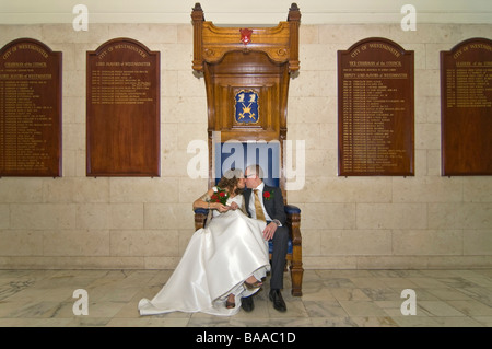 Orizzontale ad angolo ampio ritratto di sposi novelli sposi seduti insieme su un grande trono formale stile sedia in legno Foto Stock