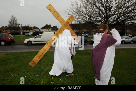Un adolescente porta una croce sulle spalle come egli gioca la parte di Gesù in una nuova promulgazione della Passione il servizio sul Venerdì Santo Foto Stock