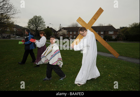 Un adolescente porta una croce sulle spalle come egli gioca la parte di Gesù in una nuova promulgazione della Passione il servizio sul Venerdì Santo Foto Stock
