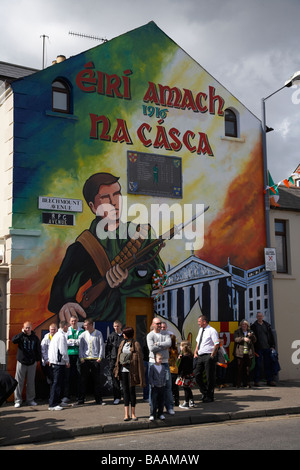 Le persone si radunano su beechmount avenue al di sotto della pasqua murale in salita la domenica di Pasqua per commemorare la pasqua in salita sulla cade Foto Stock