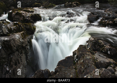 Lo spostamento acqua lattiginosa a Swallow Falls, Betws-y-Coed, Snowdonia, Galles. Foto Stock