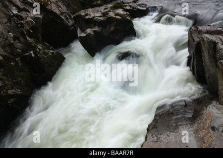 Lo spostamento acqua lattiginosa a Swallow Falls, Betws-y-Coed, Snowdonia, Galles. Foto Stock