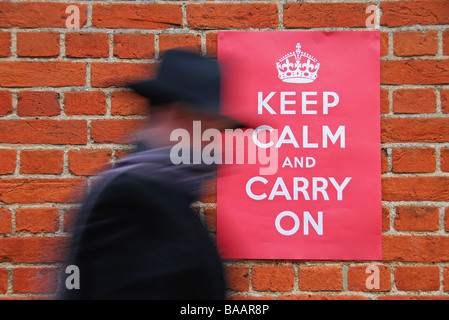 Uomo che cammina davanti ad una seconda guerra mondiale poster invitando la gente a mantenere la calma e a portare. Foto Stock