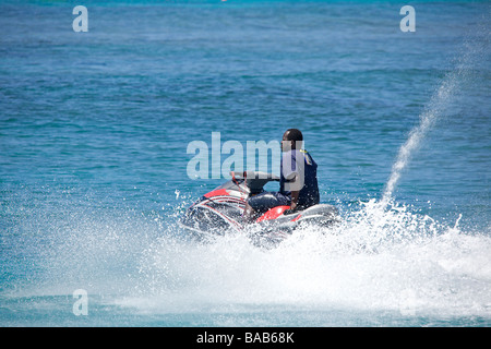 Local Bajan uomo a cavallo su un 'Jet Ski' o acqua Personal Craft (PWC) nella West Coast di Barbados, 'West Indies' Foto Stock