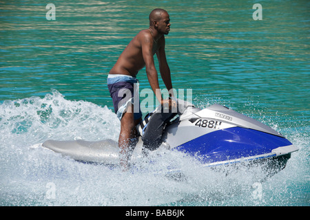 Local Bajan uomo a cavallo su un 'Jet Ski' o acqua Personal Craft (PWC) nella West Coast di Barbados, 'West Indies' Foto Stock