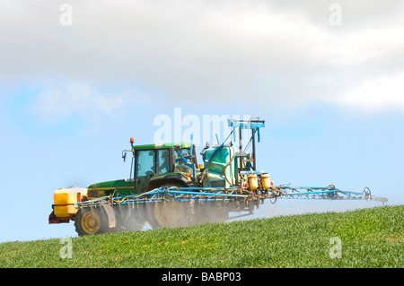 Irrorazione primaverile con trattore nel campo rurale Devon vicino a Salcombe, West Country, Inghilterra, Regno Unito Foto Stock