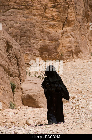 Un beduino donna che indossa un nero panno Niqab vagare all'antica Nabatean città di Petra in Giordania Foto Stock