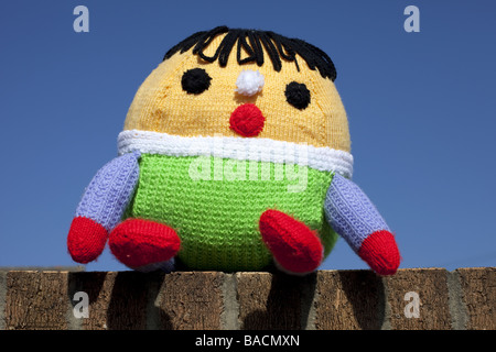 Un Humpty Dumpty giocattolo morbido sat sul muro con un cielo blu sullo sfondo. Foto Stock