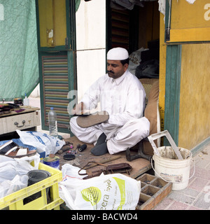 Un asiatico shoe repair e lustrascarpe uomo al suo sulla strada booth a Doha in Qatar Foto Stock