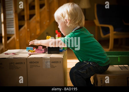 Bambino gioca con giocattoli su scatole di cartone Foto Stock