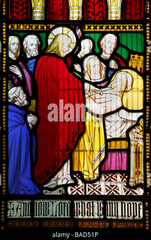 Rappresentazione di Cristo la guarigione di una donna malata sulla finestra di vetro colorato. La didascalia recita: e ora signore qual è la mia speranza Foto Stock
